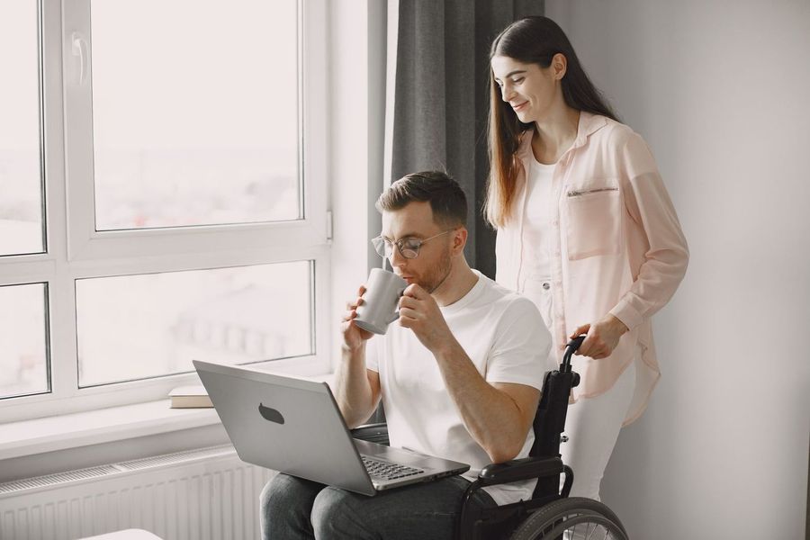Begeleider en cli&euml;nt werken samen achter een laptop.